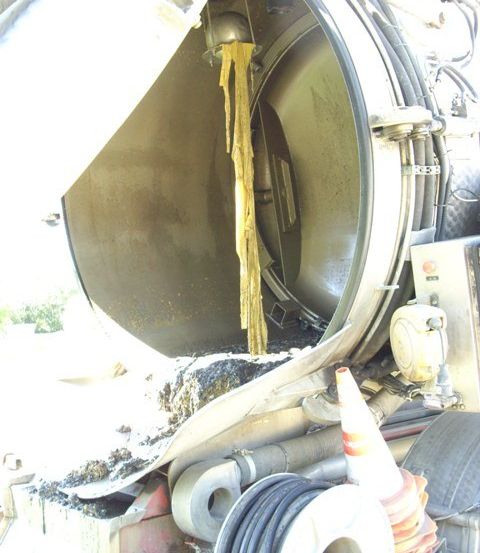 Das Innere eines beschädigten mechanischen Geräts zeigt ein hängendes gelbes Material. Es gibt Kabel, einen Verkehrskegel und andere Gegenstände darum herum.