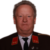 Ein älterer Mann in einem Militäruniform mit roten Schulterklappen und einer schwarzen Krawatte posiert ernst vor schwarzem Hintergrund.