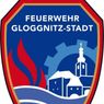 A blue and red emblem with 'Feuerwehr Glognitz-Stadt' written in white above a depiction of a church, buildings, and flames.