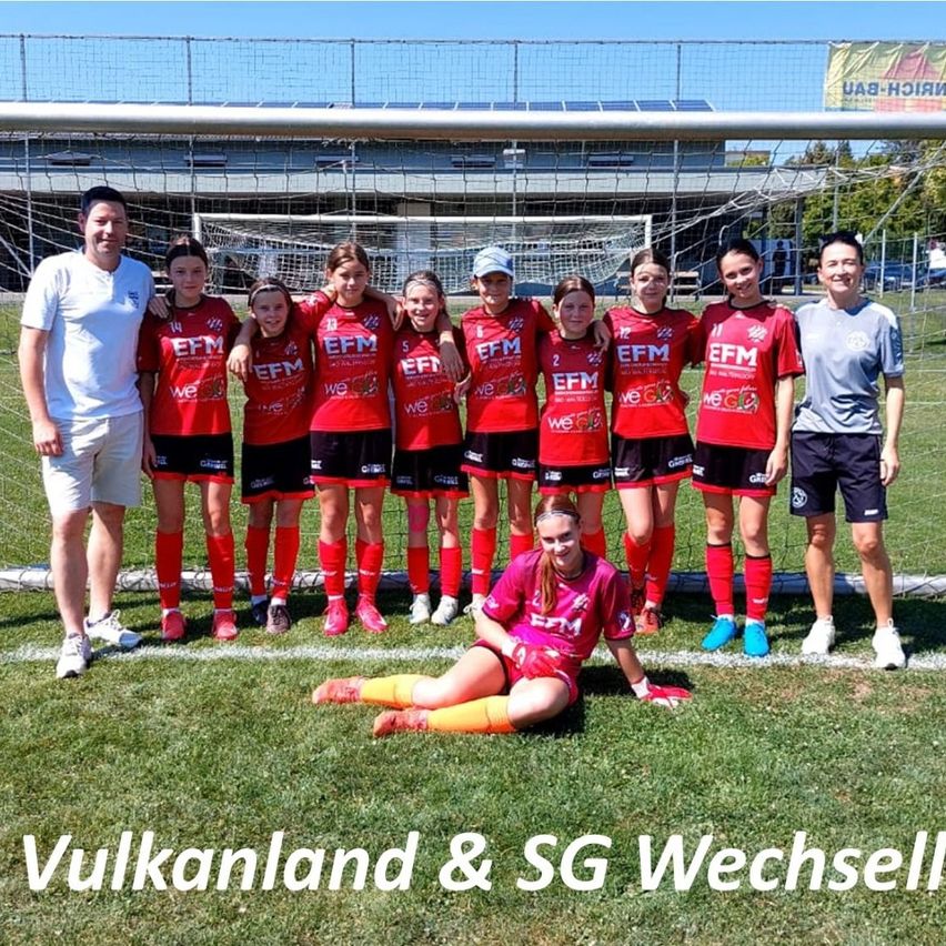 Eine Fußballmannschaft, die rote Trikots mit EFM und der Nummer 2 auf dem Rücken trägt, posiert für ein Foto auf einem Feld mit einem Tor.