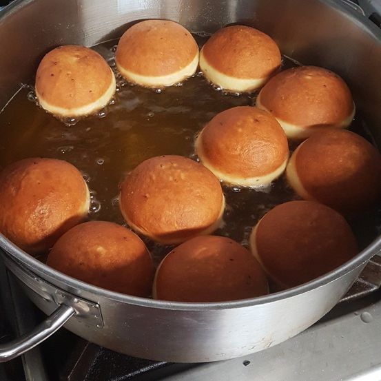 Ein Topf mit goldbraunen Donuts kocht in Öl, einige bereits gekocht, während andere im blubbernden Flüssigkeit schwimmen.