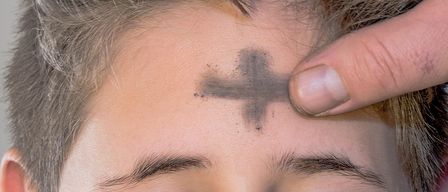 Ein Mensch mit geschlossenen Augen und einem Kreuz aus Asche auf der Stirn.