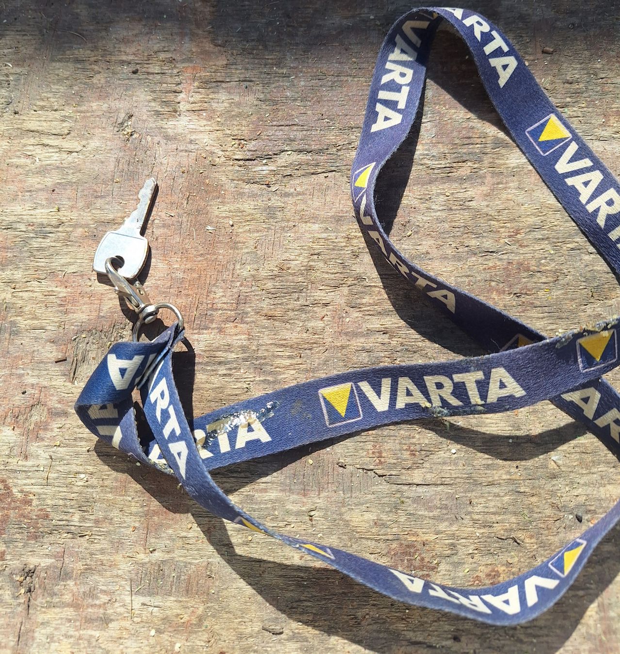 Ein blaues Namensschild mit dem Wort VARTA in weißer Schrift. Ein Schlüssel ist daran befestigt.