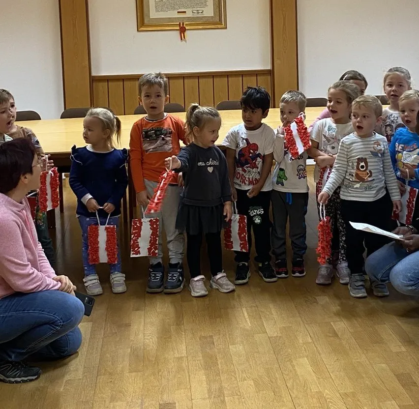 Kinder mit Geschenken in Rot-Weiß-Optik stehen Spalier.