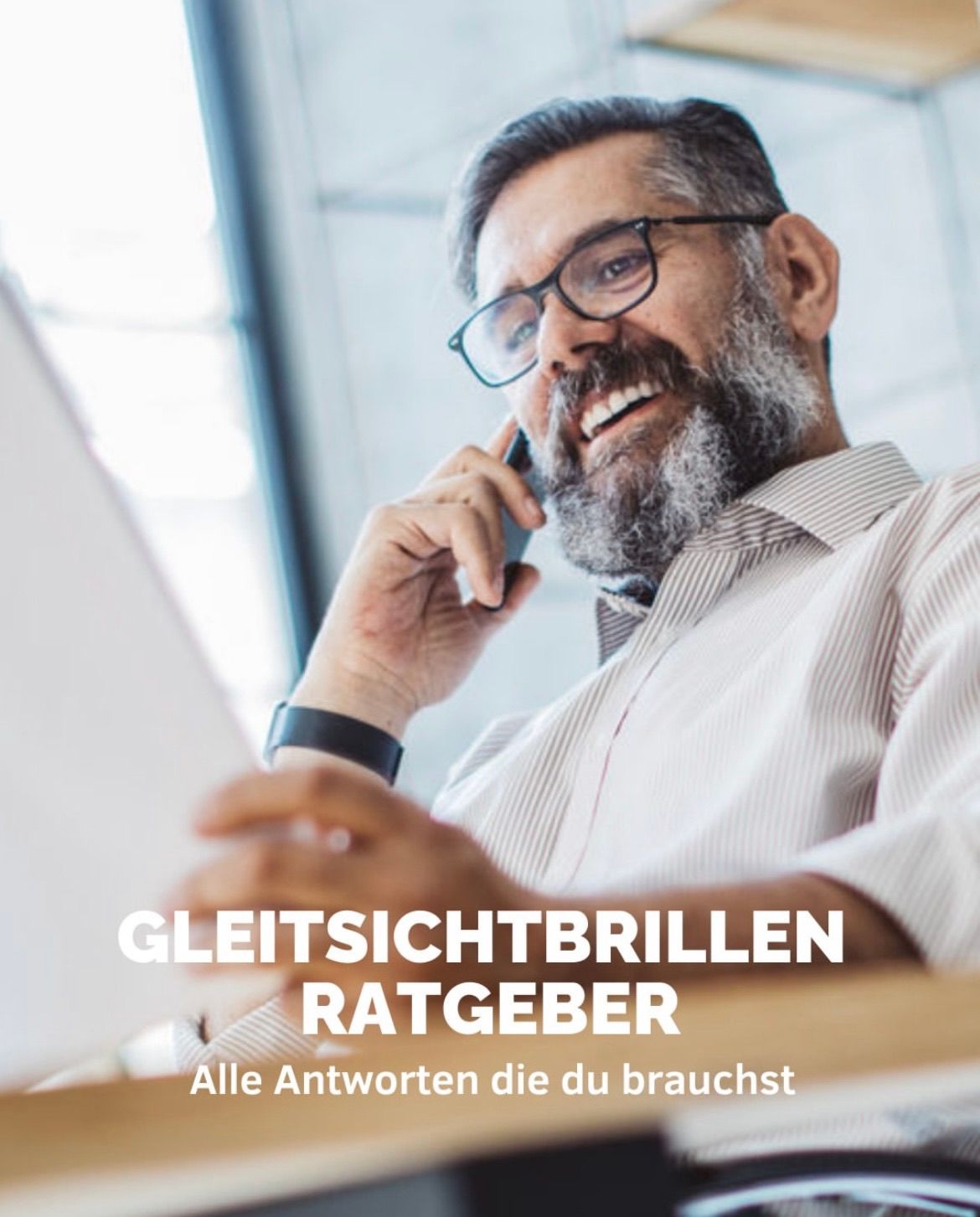 Ein Mann mit Bart hält ein Telefon, lächelt und schaut auf ein Papier vor ihm. Der Text auf dem Bild lautet 'GLEITSICHTBRILLEN RATGEBER'. Er trägt eine Brille und eine Uhr.