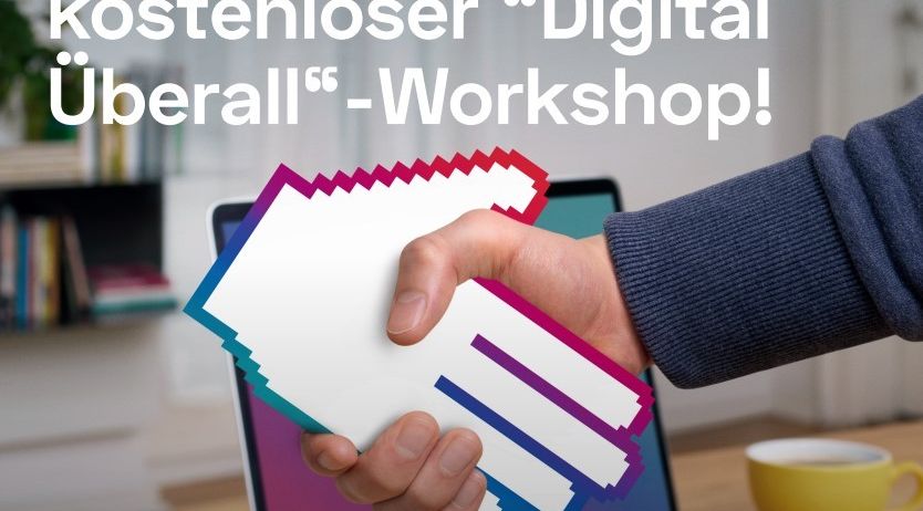 Ein Bild zeigt eine Hand, die ein Papiersymbol mit dem Text 'Digital überall' hält. Es ist auf einem Laptop mit buntem Bildschirm, in der Nähe einer Tasse und Büchern.