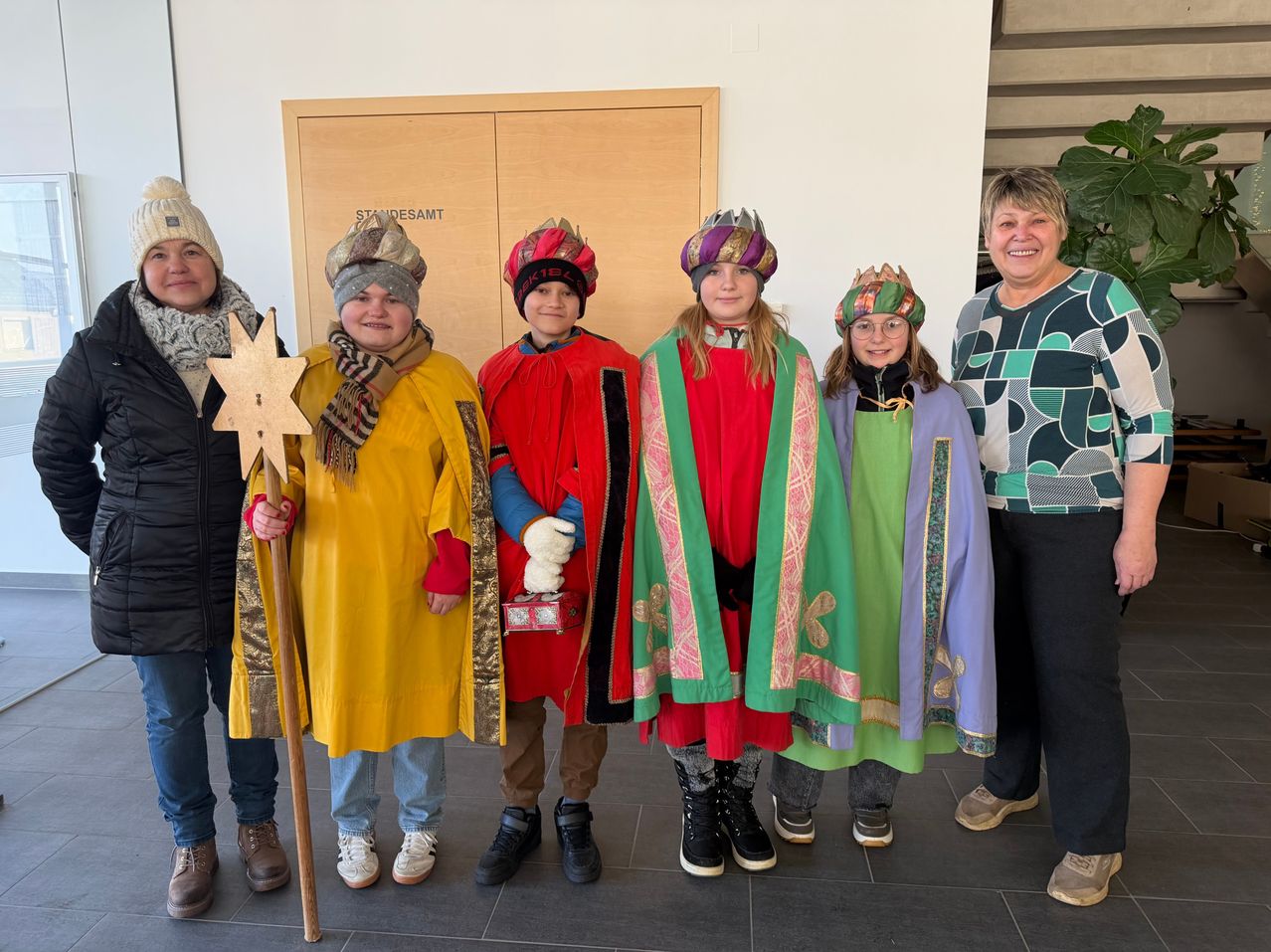 Eine Gruppe von Menschen in bunten Kostümen und Mützen posiert für ein Foto. Sie scheinen einen festlichen Anlass zu feiern.