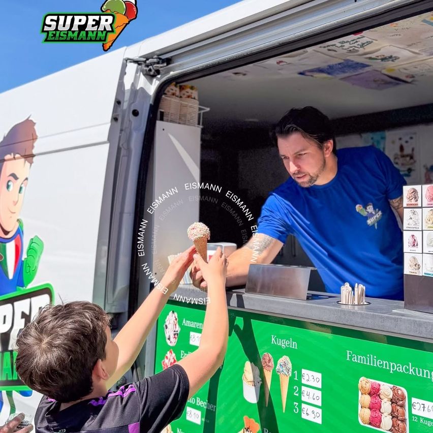 Eismann übergibt einem Jungen in Wien ein Eis vom Eiswagen.