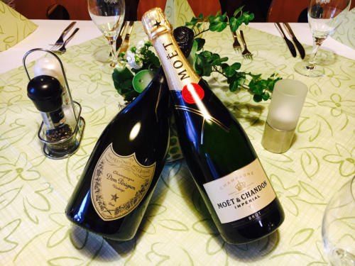 Zwei Flaschen Champagner auf einer Tischdekoration mit Blumen, Weingläsern, einer Kerze und einem Salzstreuer.