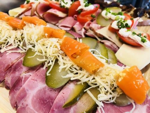 Eine Nahaufnahme einer Charcuterie-Platte mit Schinkenscheiben, Gurken, Käse und Tomaten mit Garnierungen.