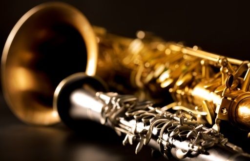 Eine Nahaufnahme eines goldenen Saxophons und einer Klarinette mit komplizierten Designs auf schwarzem Hintergrund.