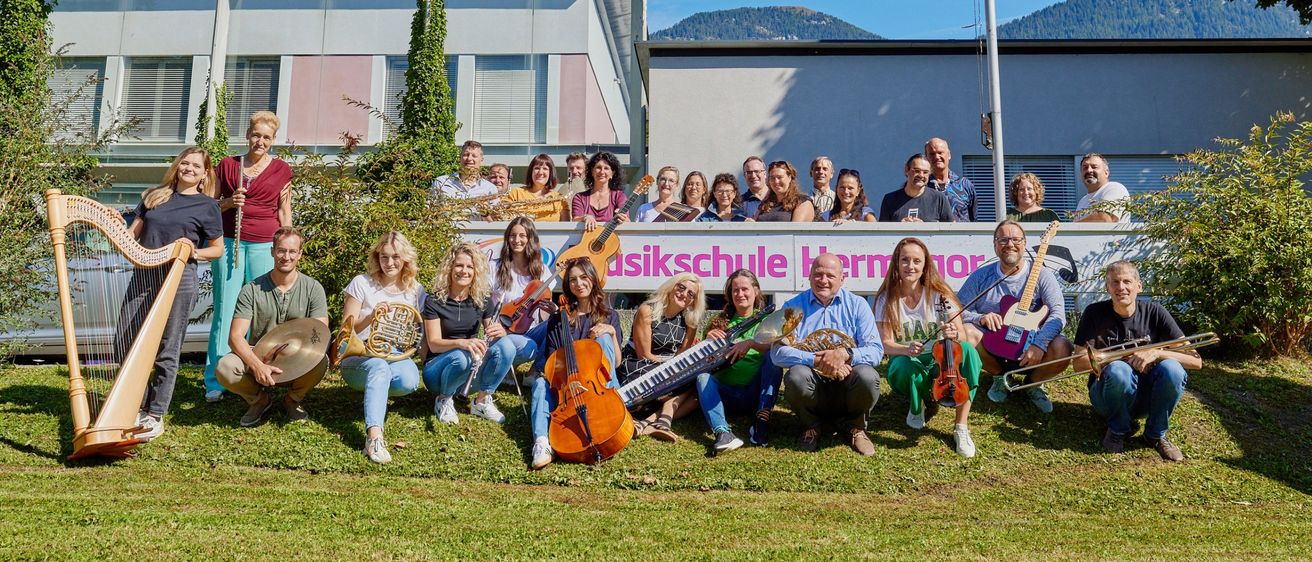 Eine Gruppe von Musikern steht vor einem Gebäude mit einem Schild, das Musikschule Bern besagt. Sie halten verschiedene Musikinstrumente und posieren für ein Foto.