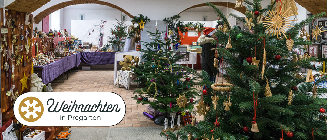 Ein Raum voller mehrerer geschmückter Weihnachtsbäume, einer Person in einem Weihnachtsmannhut und einem Teddybären auf einem Tisch. Der Raum hat Ziegelboden und ein Wasserzeichen mit dem Wort 'Lichten'.