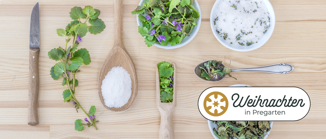 Ein hölzerner Löffel mit Salz und Kräutern auf einem Holztisch. Die Kräuter umfassen Minze und andere Grüns.