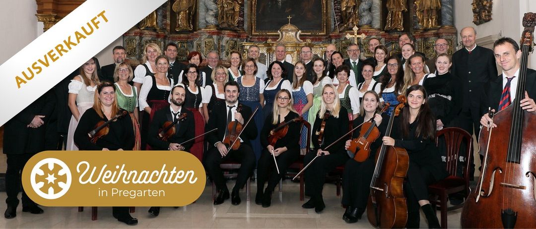 Eine Gruppe von Musikern in formeller Kleidung, darunter Männer und Frauen, posiert für ein Foto und hält Violinen und Celli in einer Kirchenumgebung.