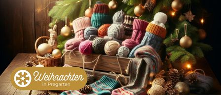 Ein Holzkasten voller bunter Wolle und gestrickter Artikel, einschließlich Mützen, Schals und Socken, steht unter einem geschmückten Weihnachtsbaum mit Ornamenten und Lichtern.
