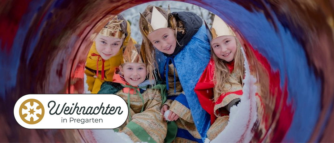 Vier Kinder in festlichen Kostümen lächeln und posieren für ein Foto. Sie tragen Kronen und der Hintergrund ist verschneit.