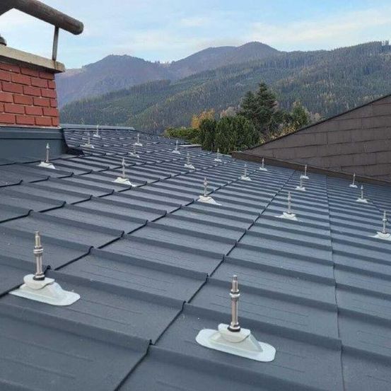 Ein Dach mit mehreren Metallpfosten und einem Schornstein, vor einem Gebirgshintergrund.