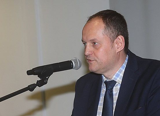 Ein Mann in einem Anzug spricht in einer Konferenz in ein Mikrofon.