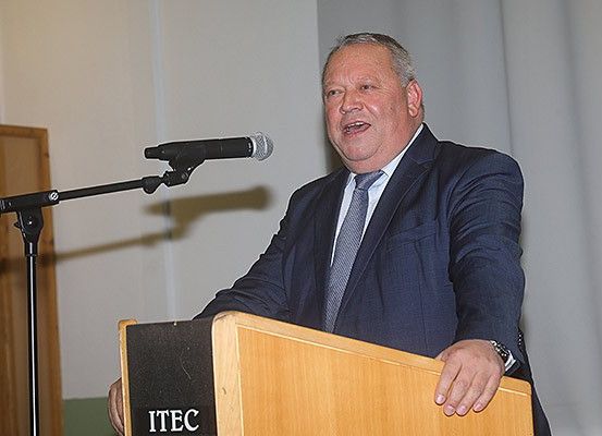 Ein Mann in Anzug und Krawatte steht an einem Rednerpult mit Mikrofon. Das Rednerpult hat die Buchstaben ITEC darauf.