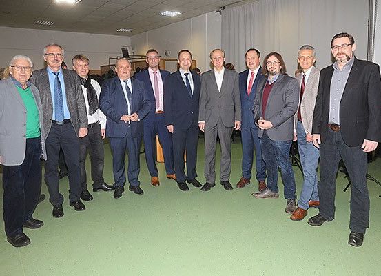 Eine Gruppe von Männern in formeller Kleidung steht zusammen in einem Raum, möglicherweise für ein Gruppenfoto.