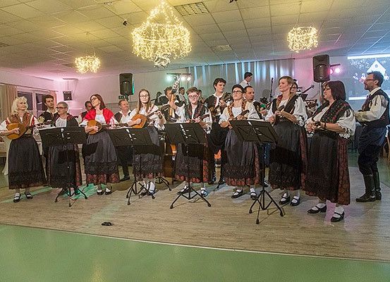 Eine Gruppe von Musikern spielt auf einer Bühne mit Musikinstrumenten, darunter Gitarren, unter Kronleuchtern.