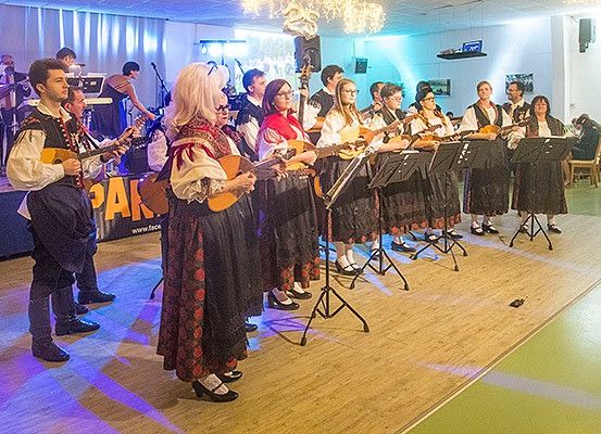Eine Gruppe von Musikern in traditioneller Kleidung spielt Gitarren und singt auf der Bühne. Im Hintergrund spielen einige Leute verschiedene Instrumente.