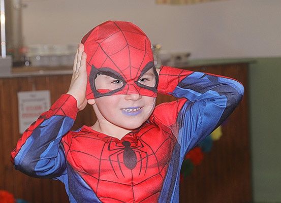 Ein junger Junge in einem roten und blauen Spider-Man-Kostüm, der sich mit beiden Händen den Kopf hält.