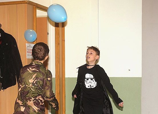 Zwei Jungen spielen mit Luftballons in einem Raum. Ein Junge trägt ein Camouflage-Hemd und der andere ein Star Wars Stormtrooper-Kostüm.