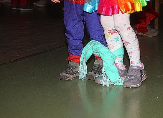 Zwei Kinder stehen eng beieinander; eines trägt ein Spider-Man-Kostüm und das andere bunte Strumpfhosen mit Blumenmustern.