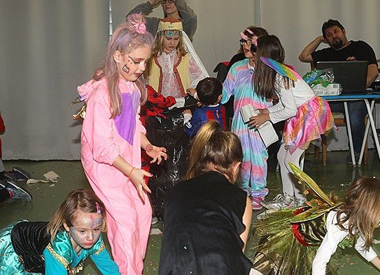 Eine Gruppe von Kindern in Kostümen spielt in einem Raum, eines trägt ein rosa Kostüm und ein anderes ein Feenkostüm.