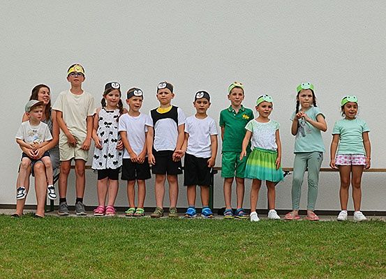 Eine Gruppe von Kindern mit Tier-Hut-Designs, die in einer Reihe auf einem Rasen stehen.