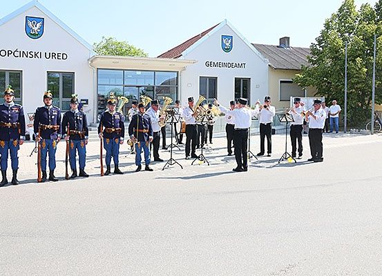 Eine Gruppe von Menschen in blauen Uniformen und Mützen steht vor einem Gebäude und spielt Musikinstrumente.