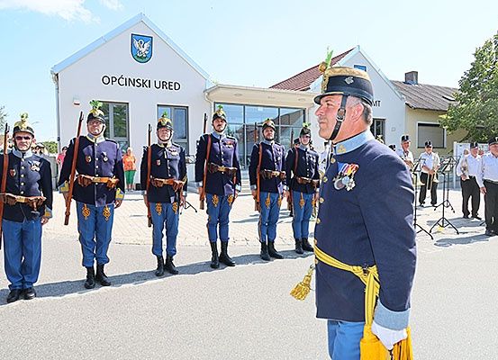 Eine Gruppe uniformierter Männer steht vor einem Gebäude mit einer Band im Hintergrund.