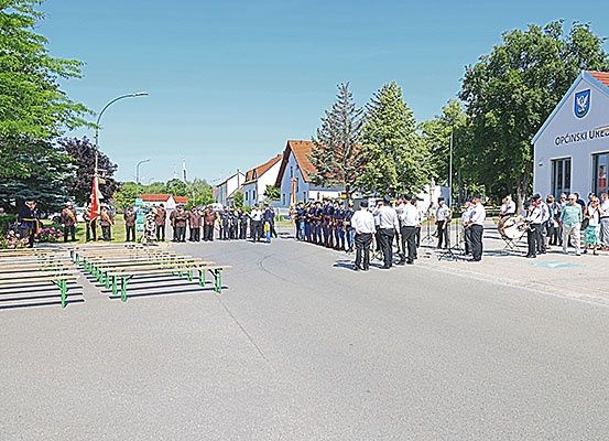 Eine Gruppe von Menschen in Uniform steht in einer Reihe, möglicherweise für eine Parade, mit einem Gebäude mit einem Logo im Hintergrund.