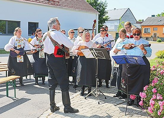 Eine Gruppe von Menschen in traditionellen Kostümen spielt Musikinstrumente im Freien.