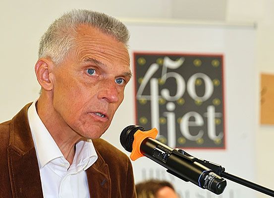Ein Mann steht vor einem Mikrofon vor einem Banner mit den Worten '450 jiet'.