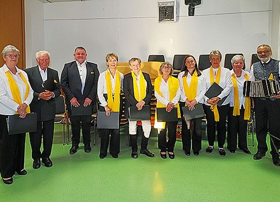 Eine Gruppe von Menschen in formeller Kleidung, die in einer Reihe stehen und Ordner halten, nimmt wahrscheinlich an einer Preisverleihung in einem Saal teil.