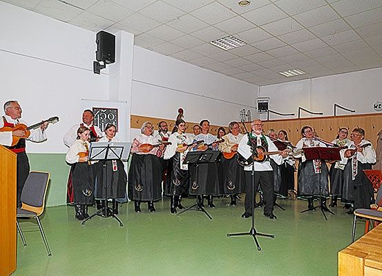 Eine Gruppe von Musikern in traditioneller Kleidung spielt mit verschiedenen Instrumenten wie Gitarren und Violinen in einem Raum.