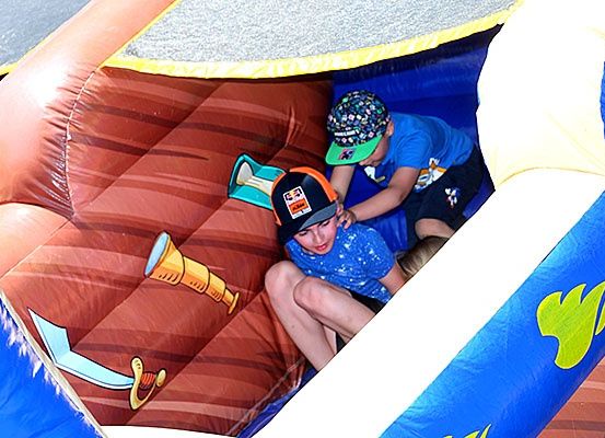 Zwei kleine Jungen krabbeln in einem pirat-thematischen aufblasbaren Spielbereich. Ein Junge trägt ein blaues T-Shirt und einen bunten Hut.