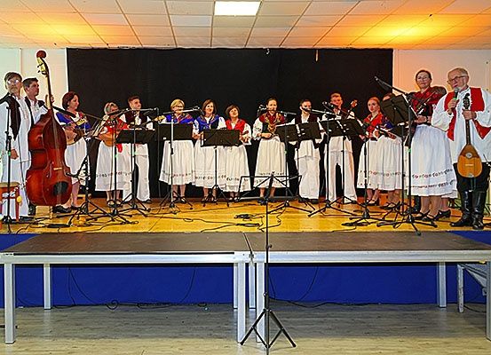 Eine Gruppe Musiker in traditioneller Kleidung tritt mit Musikinstrumenten auf einer Bühne auf.