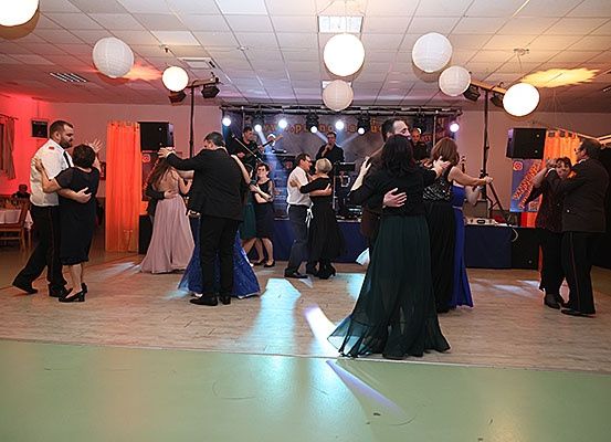 Menschen tanzen auf einer Tanzfläche mit roter Beleuchtung und Papierlaternen, begleitet von einer Live-Band auf der Bühne.