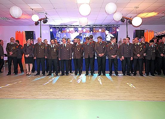 Eine Gruppe von Militäroffizieren steht auf der Bühne, gekleidet in Uniform, mit Scheinwerfern und Dekorationen im Hintergrund.