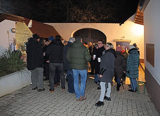 Eine Gruppe von Menschen steht in einem Außenbereich und wartet wahrscheinlich auf eine Veranstaltung. Sie sind warm gekleidet, was darauf hindeutet, dass es kalt ist.