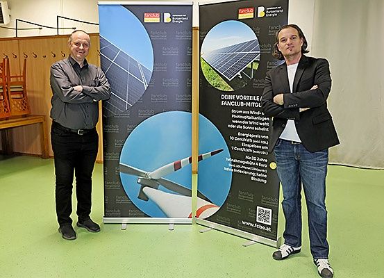 Zwei Männer stehen neben einem Banner, auf dem steht 'Ihre Vorteile mit Fanclub.' Sie scheinen erneuerbare Energie zu bewerben.
