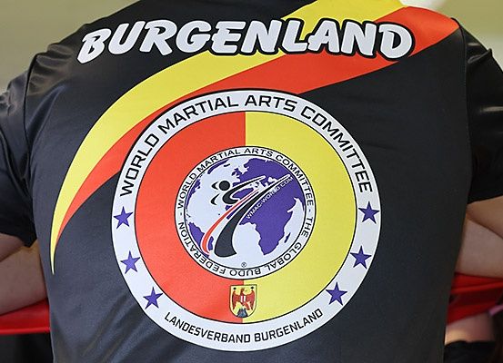 Eine Nahaufnahme eines Sporttrikots mit 'Burgenland' auf dem Rücken und einem Welt-Kampfsportverband-Logo auf der Vorderseite.