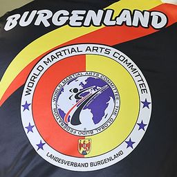 Eine Nahaufnahme eines Sporttrikots mit 'Burgenland' auf dem Rücken und einem Welt-Kampfsportverband-Logo auf der Vorderseite.