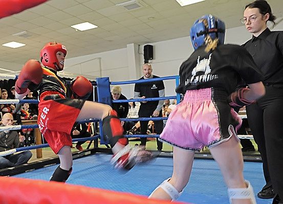 Zwei Boxer kämpfen in einem Ring, einer trägt Rot und der andere Pink, während Zuschauer zuschauen.