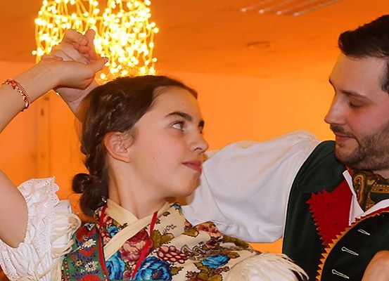 Ein Mann und eine Frau tanzen, die Frau in traditioneller Kleidung, unter einer Kristallleuchter.