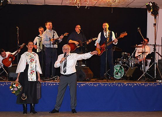 Eine Band tritt auf der Bühne auf. Der Mann in der Mitte singt in ein Mikrofon, während die anderen verschiedene Instrumente spielen.
